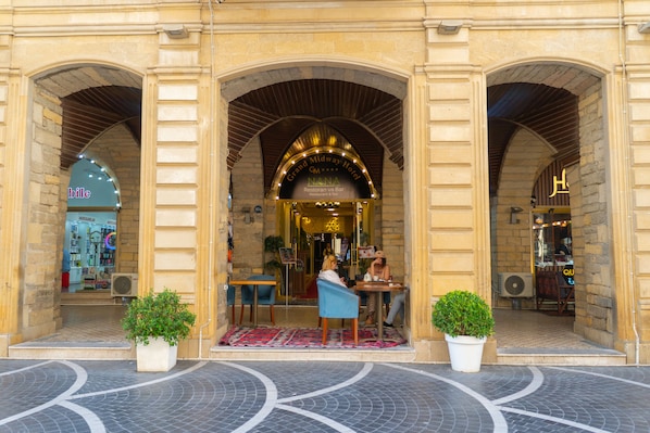 A hotel entrance with a grand archway, outdoor seating area, and potted plants.