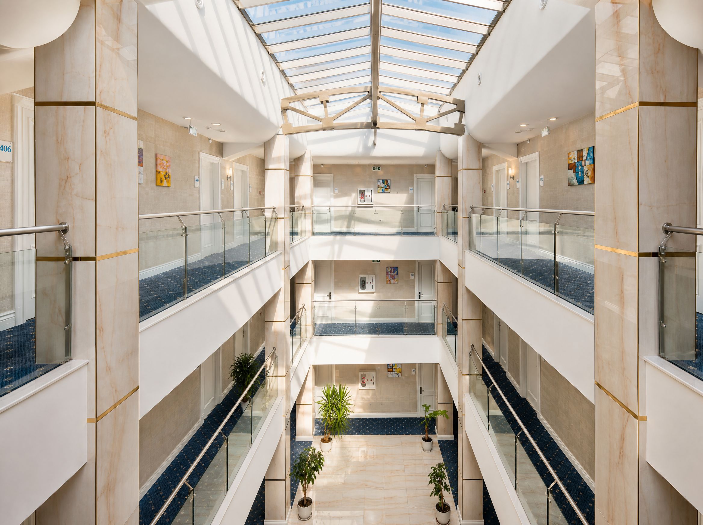 A multi-level atrium with glass railings, marble floors, and potted plants.