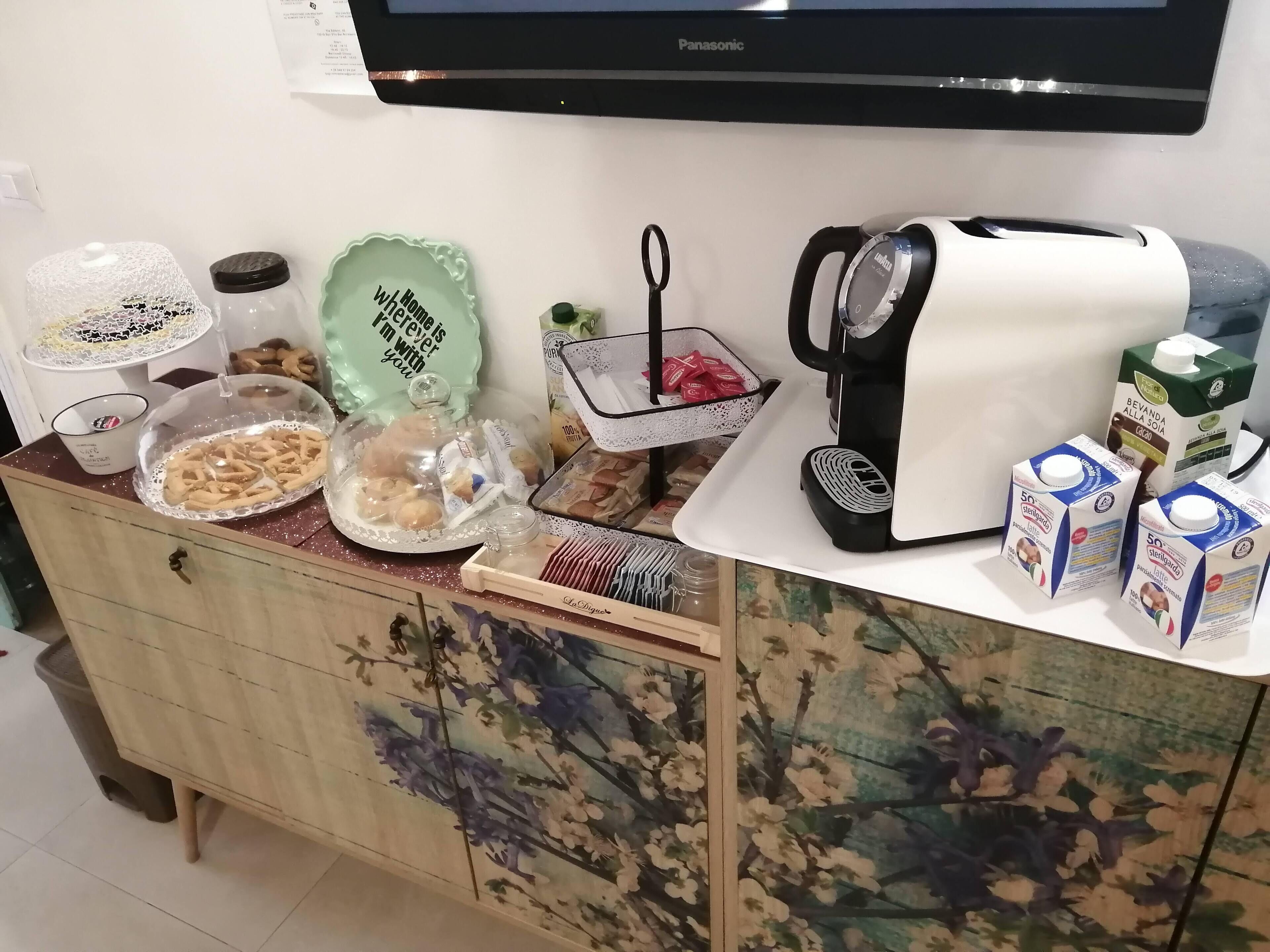 Keittiön työtasolla on kahvinkeitin, maitotölkkejä, lautanen ruokaa varten ja koristeellinen lautanen, jossa on jokin viesti.