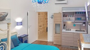 A bedroom with a bed, a desk, and a kitchenette. - Borgo Salentino (San Vito dei Normanni)