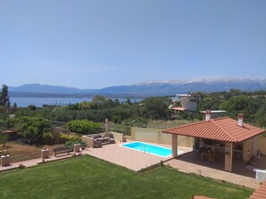 Propiedad residencial con piscina, muebles de patio y vistas a un lago y montañas.
