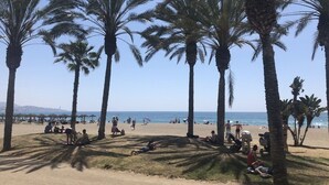 A beach with palm trees and people relaxing. - Apartment on the beachfront overlooking the sea of Alboran, in the Malagueta. (Málaga)