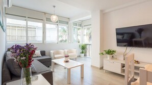 A modern living room with a sofa, two armchairs, a coffee table, and a TV mounted on the wall. - Apartment on the beachfront overlooking the sea of Alboran, in the Malagueta. (Málaga)