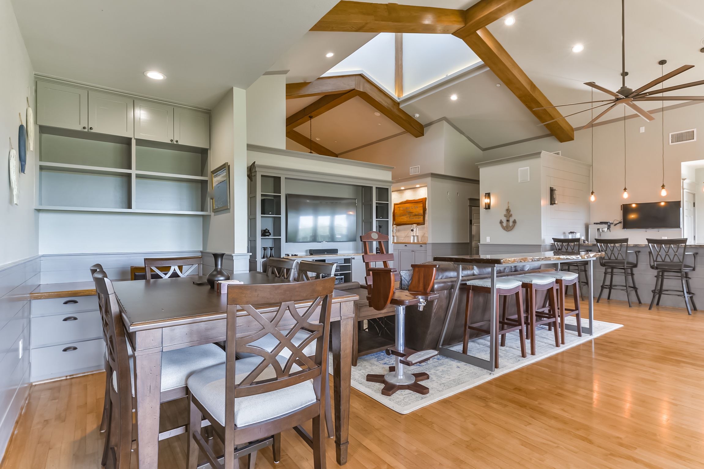 A spacious kitchen with wooden beams, a dining area with a large table and chairs, and a bar with stools.