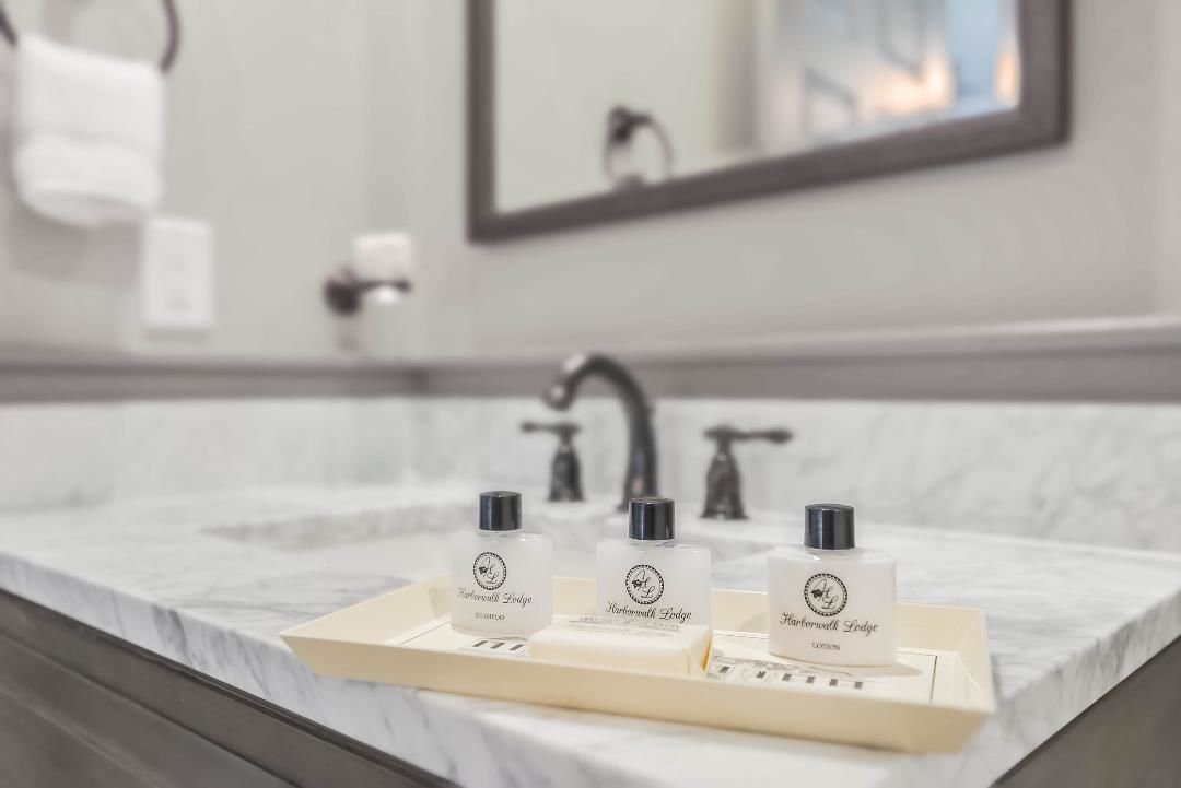 A bathroom with a marble countertop, a sink, and three bottles of Barrowwalk Lodge products.