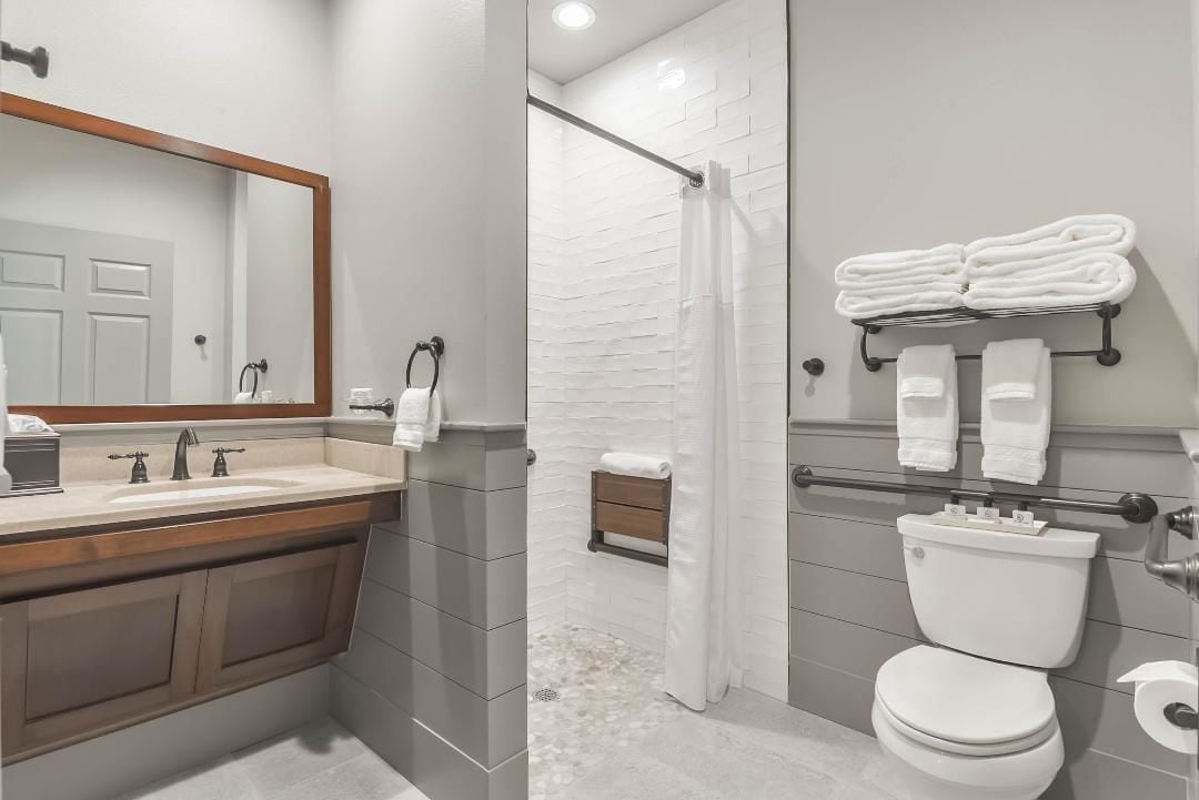 A modern bathroom with a sink, mirror, and toilet.