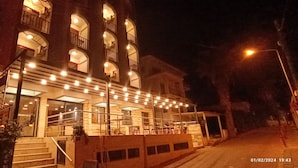 A multi-story building with a balcony and outdoor seating area, illuminated by string lights. - Erciyes Otel Kusadasi (Kusadasi)