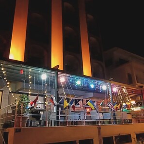 A building with a balcony adorned with flags and string lights.