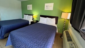 A hotel room with two beds, a ceiling fan, a wall-mounted heater, and two signs on the wall. - Hwy 59 Motel Laredo Medical Center (Laredo)