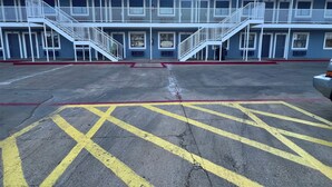 Ein Gebäude mit mehreren Zimmern, jedes mit einer Zimmernummer. Zwei Treppenhäuser führen zur oberen Etage. Der Erdgeschossbereich verfügt über einen Parkplatz mit gelben und roten Markierungen.