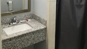 A bathroom with a granite sink, a mirror, and a shower curtain. - Hwy 59 Motel Laredo Medical Center (Laredo)