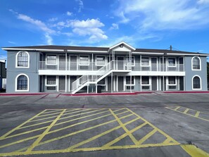 A multi-story building with a central staircase, balconies, and a parking lot with yellow markings. - Hwy 59 Motel Laredo Medical Center (Laredo)