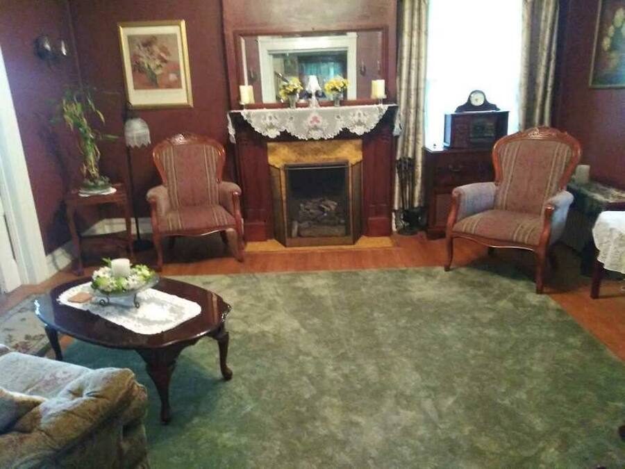 Un salon traditionnel avec une cheminée, deux fauteuils, une table basse et une table d’appoint avec une lampe.