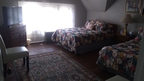 Una camera da letto con un letto, una cassettiera, una sedia e una finestra con tende.