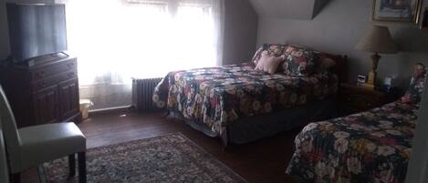 Um quarto com uma cama, cômoda, cadeira e janela com cortinas.