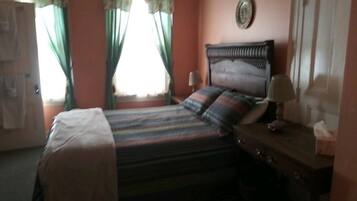 A bedroom with a bed, curtains, a bedside table, and a wall-mounted decoration.