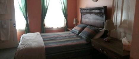A bedroom with a bed, curtains, a bedside table, and a wall-mounted decoration.