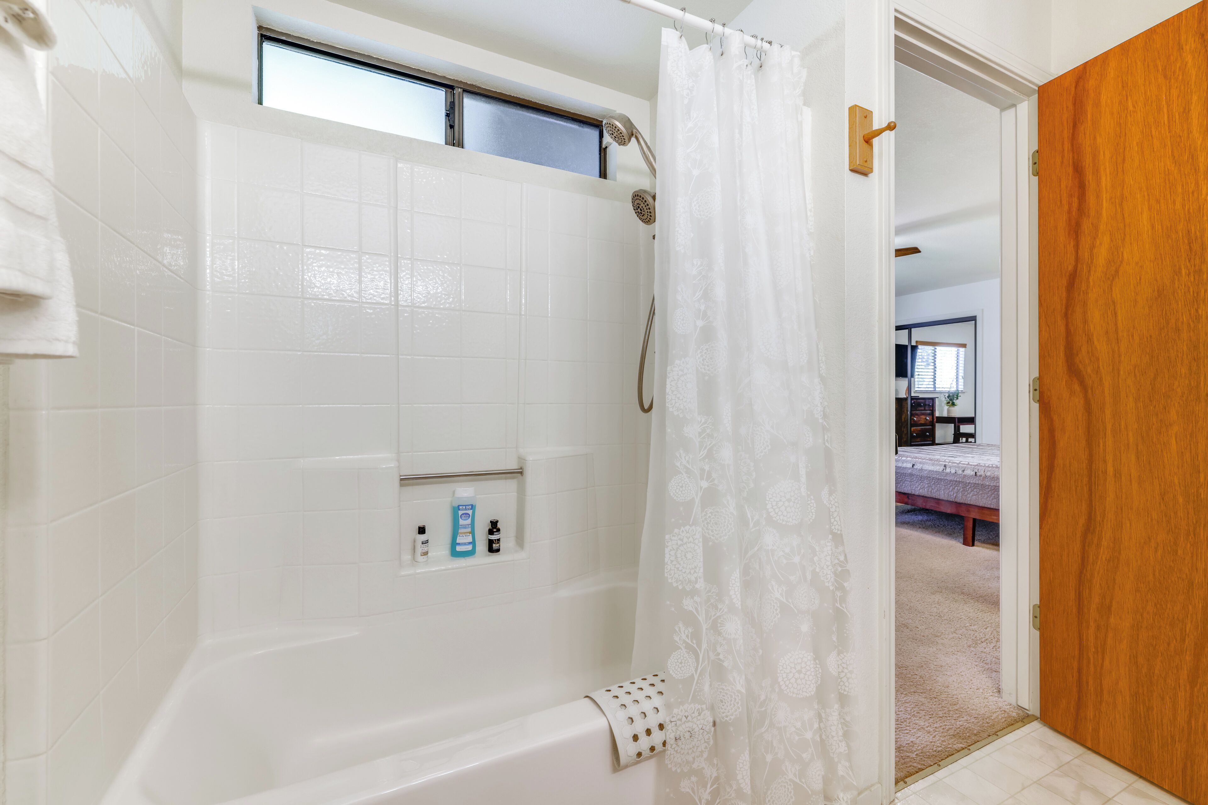 A bathroom with a bathtub, a shower, and a window.