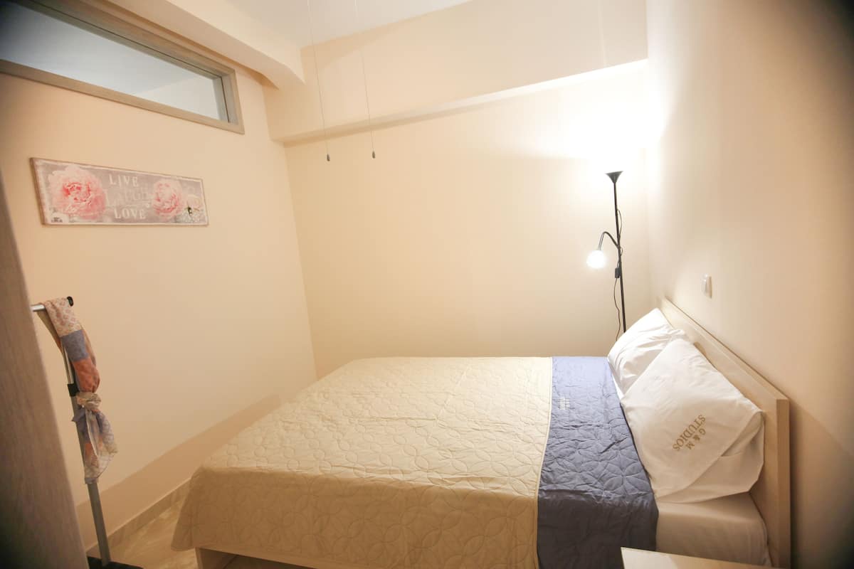 A small, neatly made bed with a quilted headboard and a single pillow.