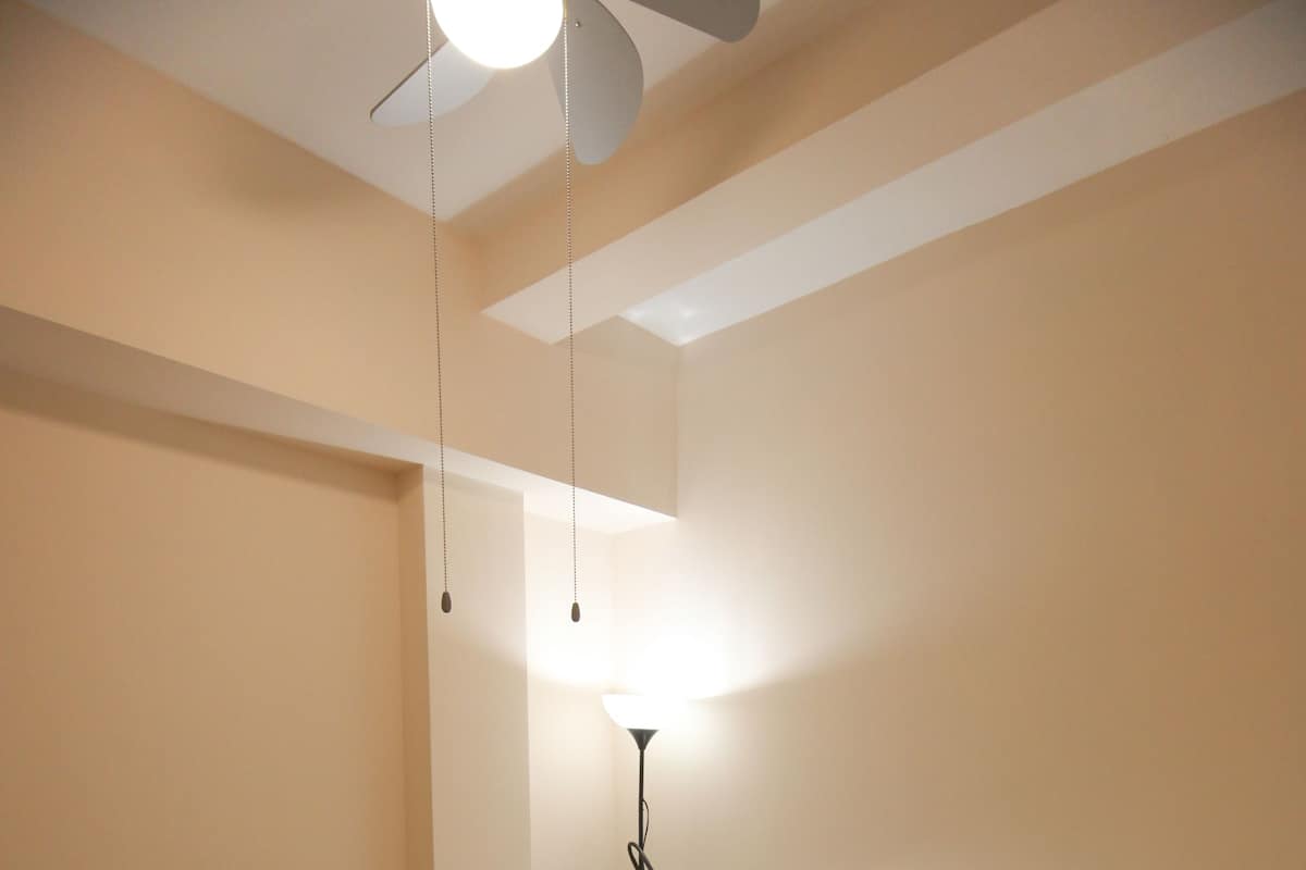 A bedroom with a bed, a ceiling fan, a bedside lamp, and a nightstand.