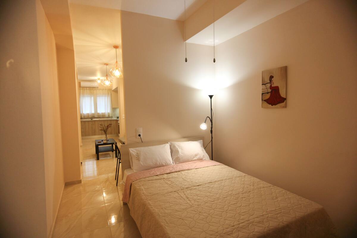A bedroom with a bed, bedside lamp, and a painting on the wall.