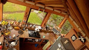 A rustic kitchen with a large window, wooden beams, and various kitchen appliances and utensils. - Mawasi Finca (Villa de Leyva)