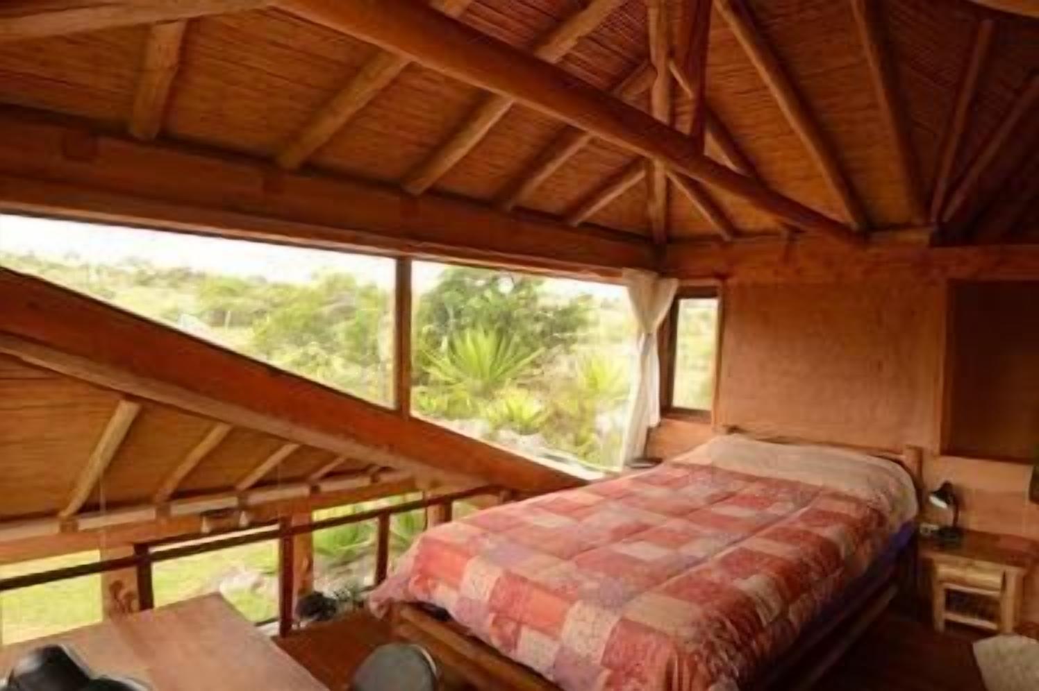 Un dormitorio con una cama grande, vigas de madera en el techo y vistas a zonas verdes.