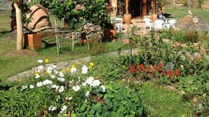 A rustic house with a tiled roof, surrounded by a garden with various plants and flowers. - Mawasi Finca (Villa de Leyva)