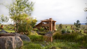 A rustic house with a tiled roof, surrounded by lush greenery and a small pond. - Mawasi Finca (Villa de Leyva)