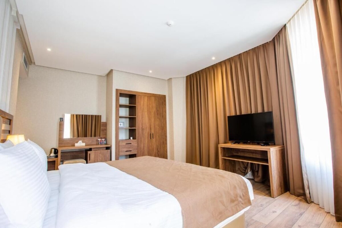A hotel room with a bed, a TV, a desk, and a wardrobe.