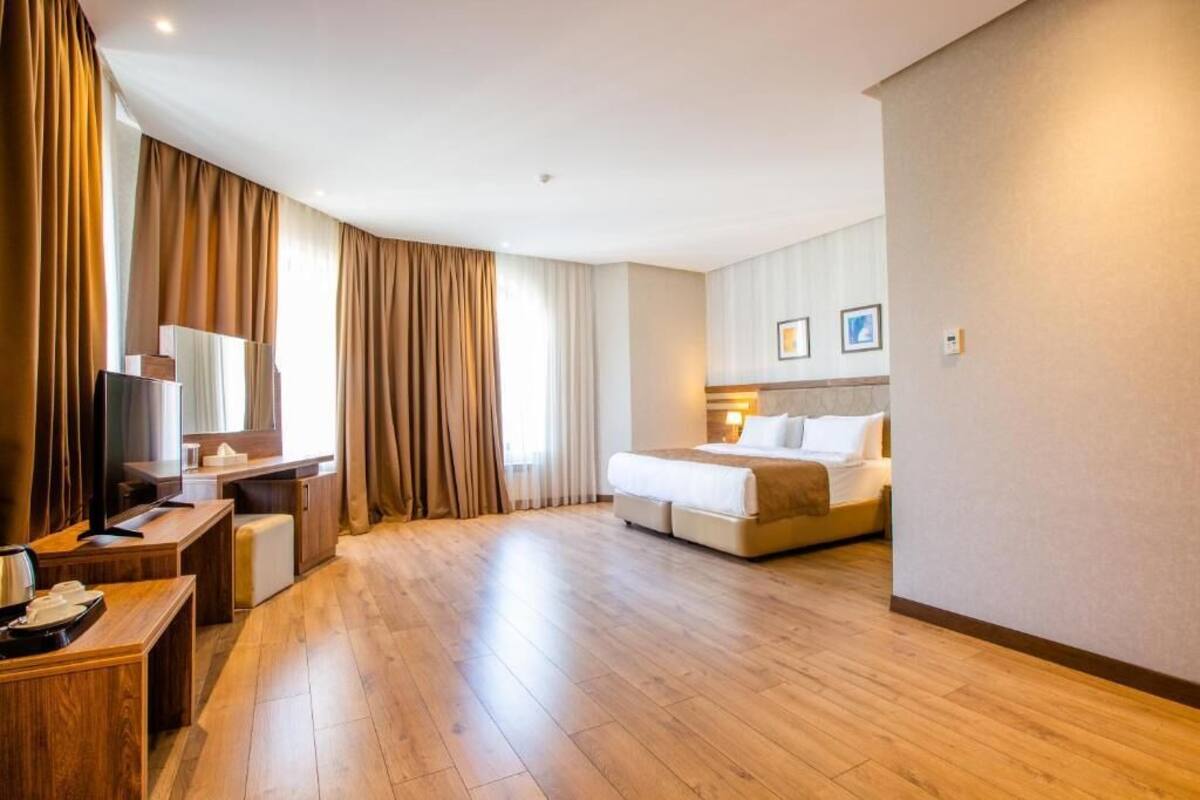 A hotel room with a bed, a desk, a TV, and curtains.