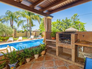 Ein Poolbereich mit Grill, Liegestühlen und Topfpflanzen.