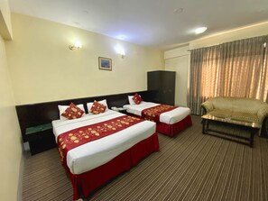 A hotel room with two beds, a sofa, a TV, and a window with curtains. - Quality Inn (Dhaka)