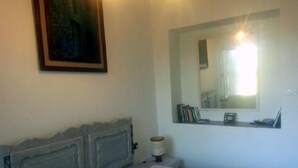Ein Schlafzimmer mit Bett, Kopfteil, Nachttisch, Spiegel und einem Fenster mit Sonneneinstrahlung.