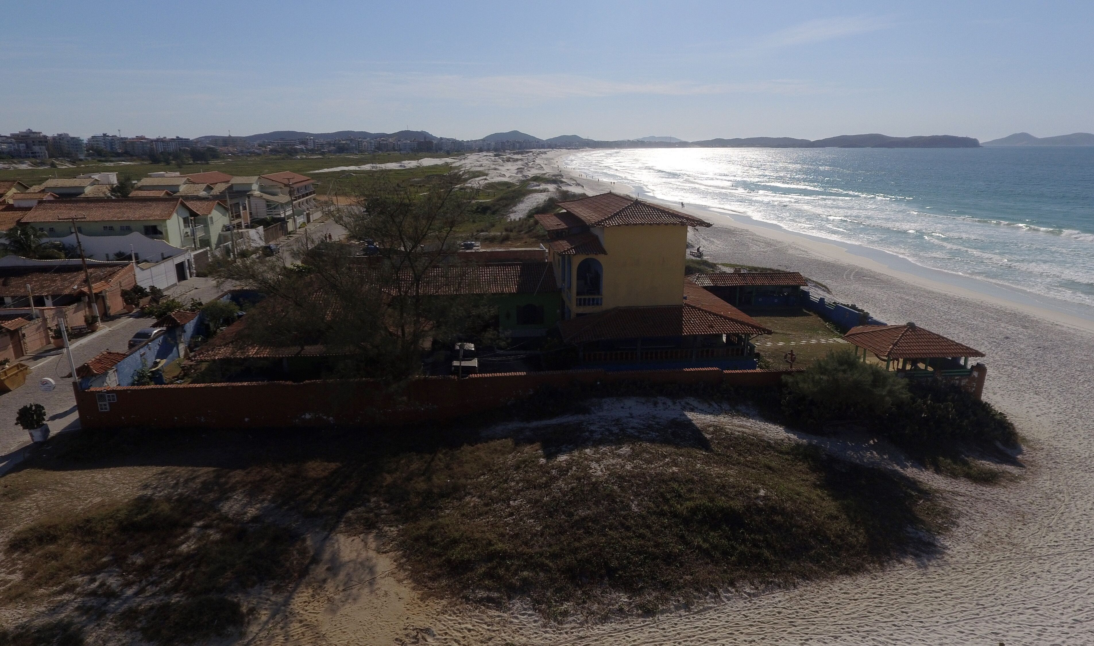 Un pueblo costero con edificios a lo largo de la playa, una vista despejada del mar y una carretera que conduce a la playa.