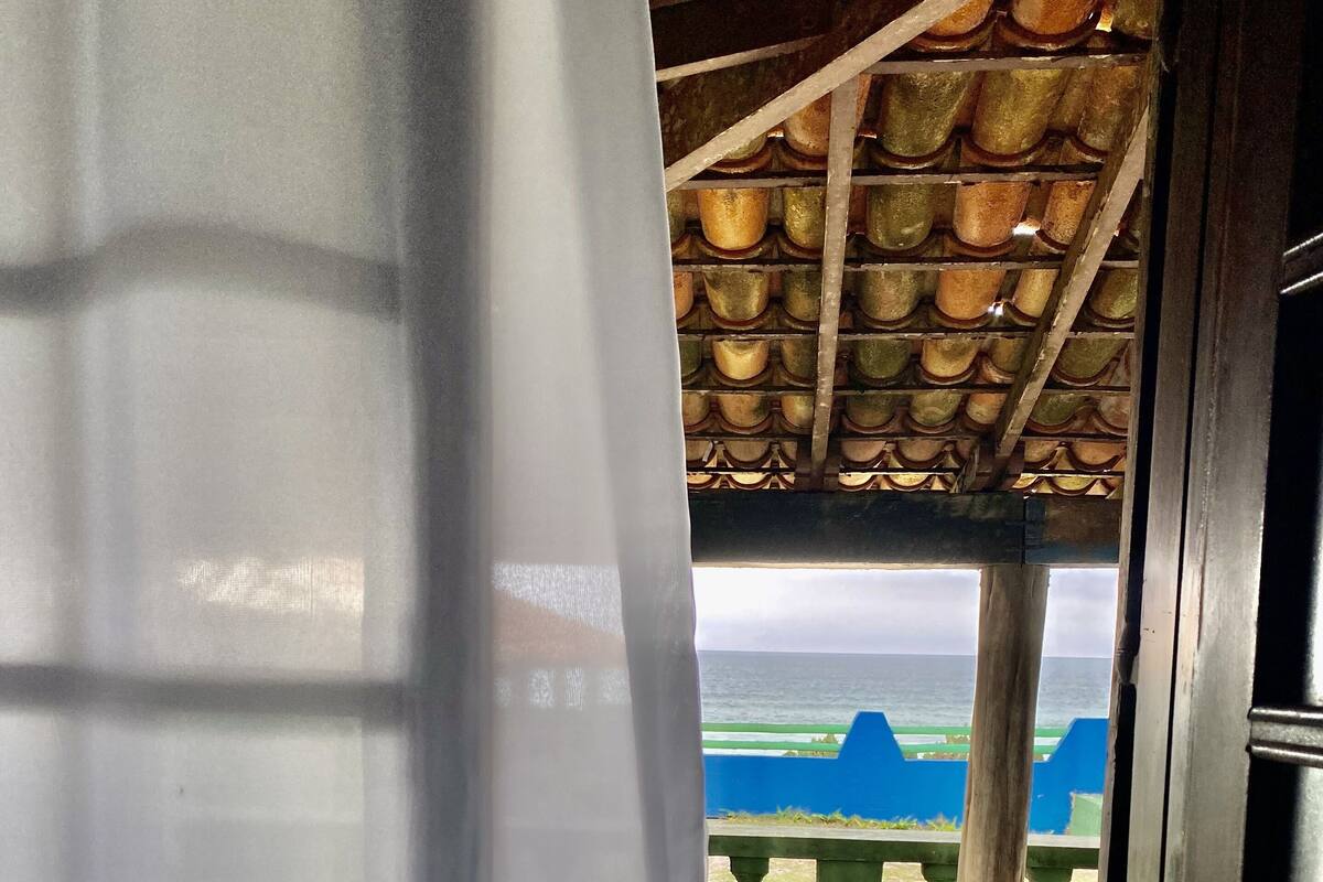 A doorway leading to a balcony with a view of the sea and a blue structure.