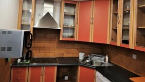 Una cocina con gabinetes rojos, una campana extractora de acero inoxidable, lavavajillas integrado y una máquina de café.