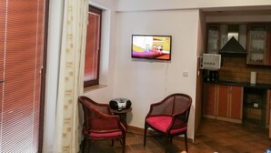 Una sala de estar con dos sillones de mimbre, un televisor y una mesita con un radio.