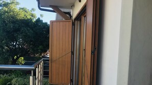 Ein Balkon mit Metallgeländer, einer Holztür und einem gefliesten Boden.