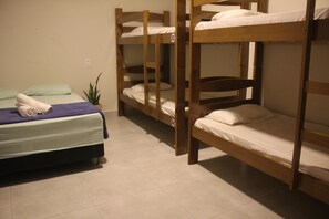 A dormitory room with bunk beds, a single bed, and a potted plant. - Massambaba Hostel (Arraial do Cabo)