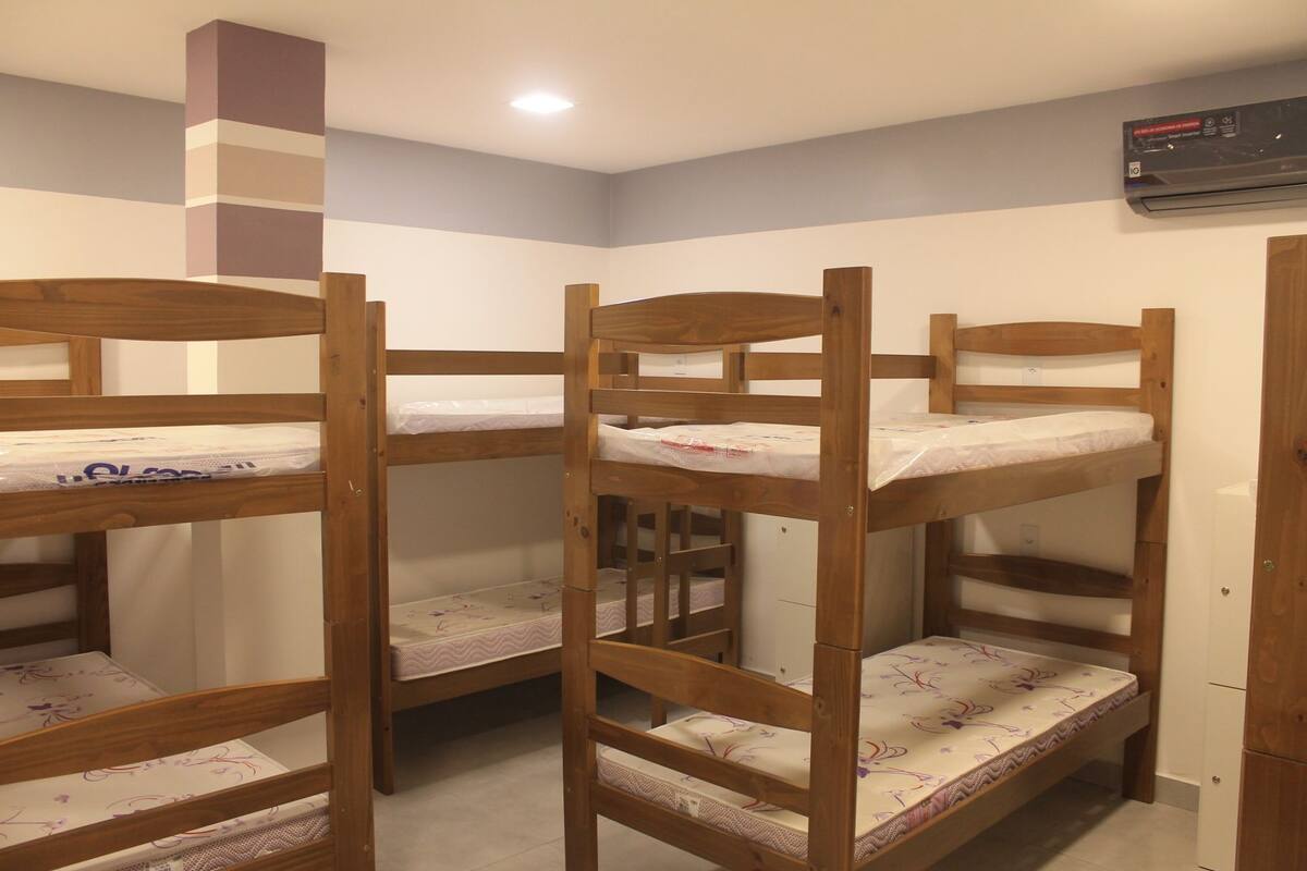 Camas literas en una habitación con pared blanca y luz de techo.
