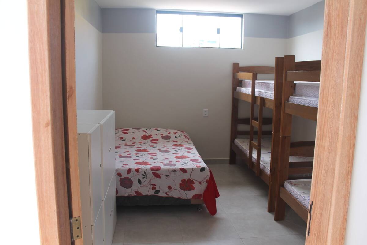 Una habitación pequeña y estrecha con una cama individual y una litera.