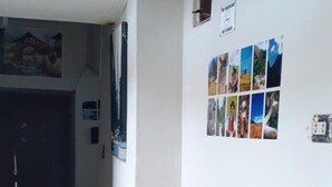 Un salon comprenant un canapé, un petit tabouret en bois et un mur décoré d’un collage de photos.