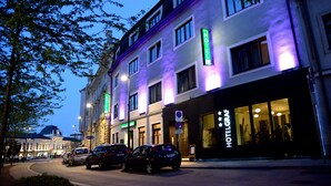 A hotel with a modern facade, multiple windows, and a neon sign indicating it is a hotel.