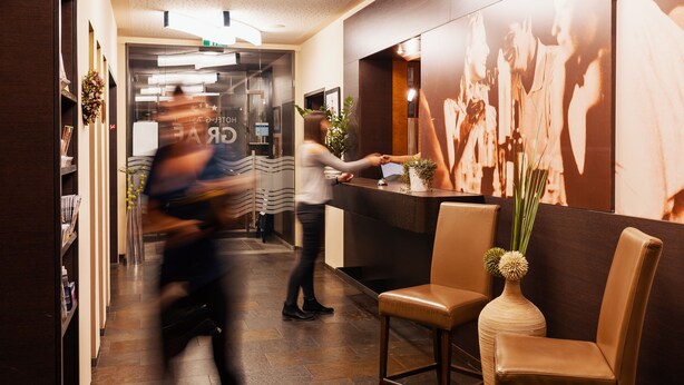 A hotel reception area with a reception desk, seating area, and a large wall mural.
