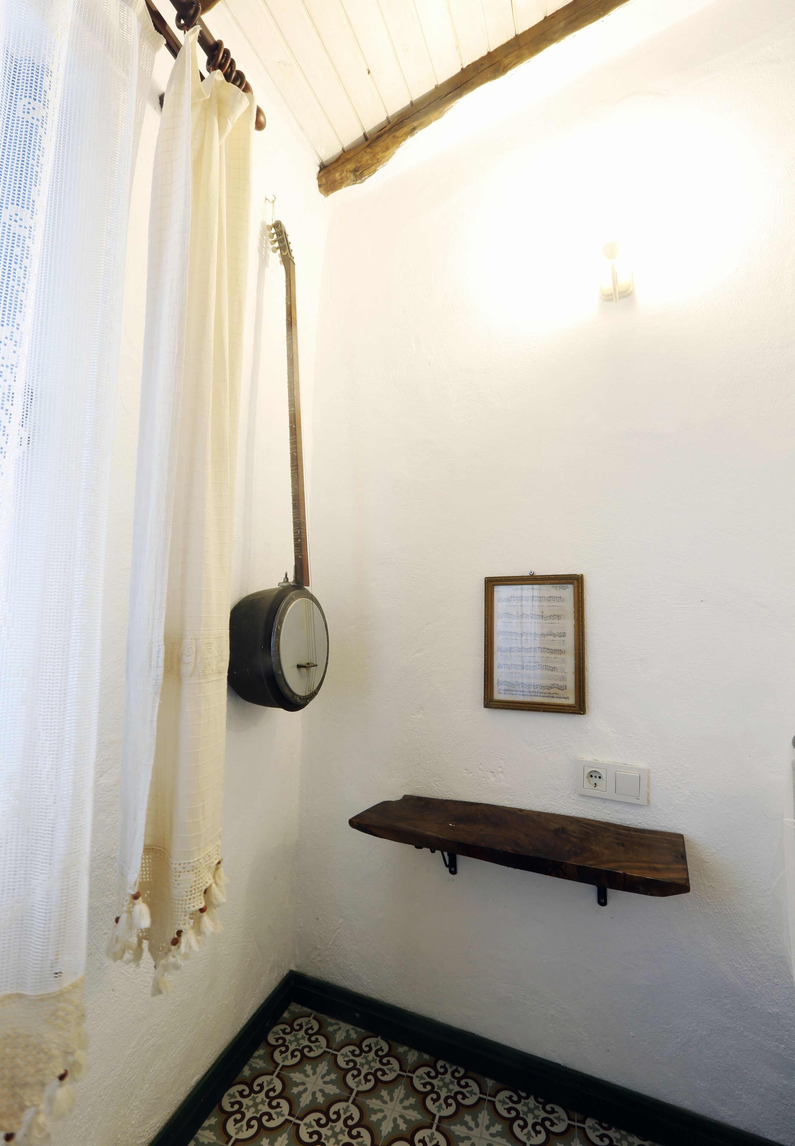 Una habitación con un banjo colgado, un menú enmarcado en la pared y un estante de madera.