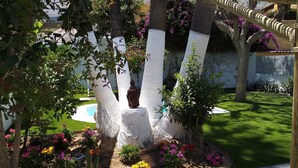 Ein Garten mit weiß gestrichenen Bäumen, einer Buddha-Statue und bunten Blumen.