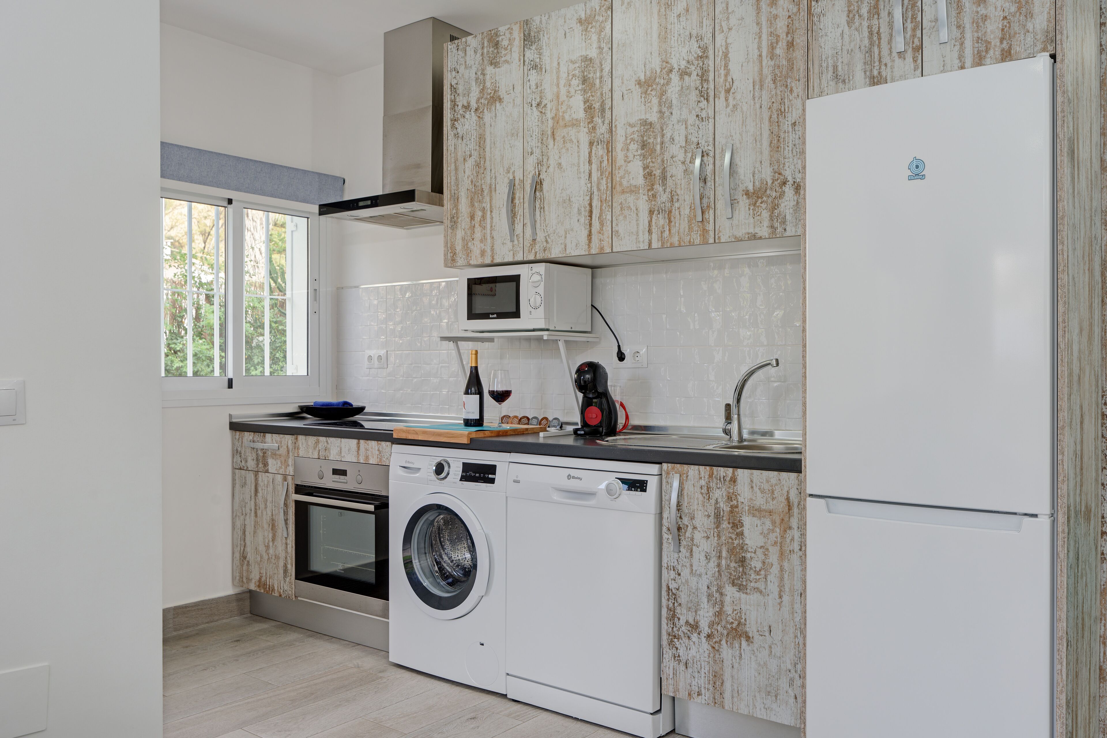 A kitchen with a washing machine, microwave, and refrigerator.