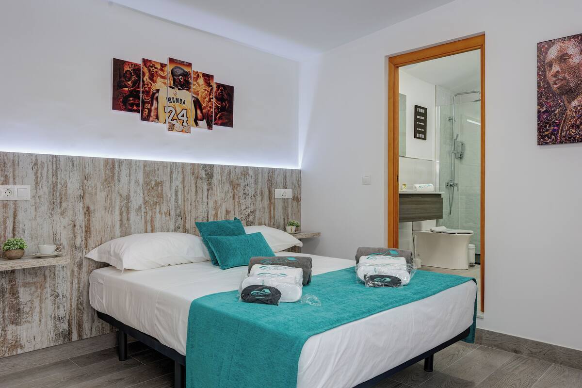 Ein modernes Schlafzimmer mit einem Bett, einem Türkis-Wurfdecken und Bildern an der Wand.