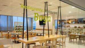 A restaurant with a modern interior, featuring glass partitions, wooden furniture, and a view of the sea. - Mia Hotel Chocó By OxoHotel (Quibdó)